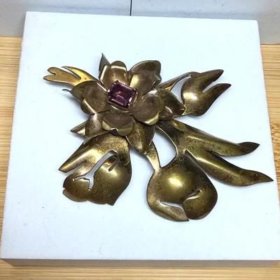 Gold tone orchid brooch with purple rhinestone center stone