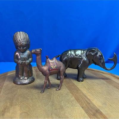 A set of three cast metal coin banks: camel, elephant, and Native American