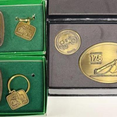 John Deere commemorative collectibles, including belt buckles, keychains, and medallions