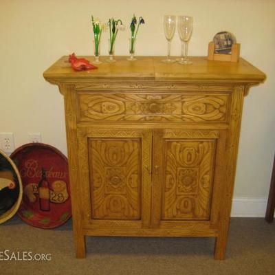 hand carved bar and wine cabinet with wine bottle cubbies, glass rack and sliding top to reveal a storage compartment