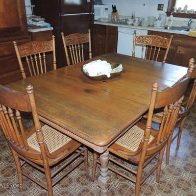 Antique oak table with six leaves and six pressed back oak caned chairs